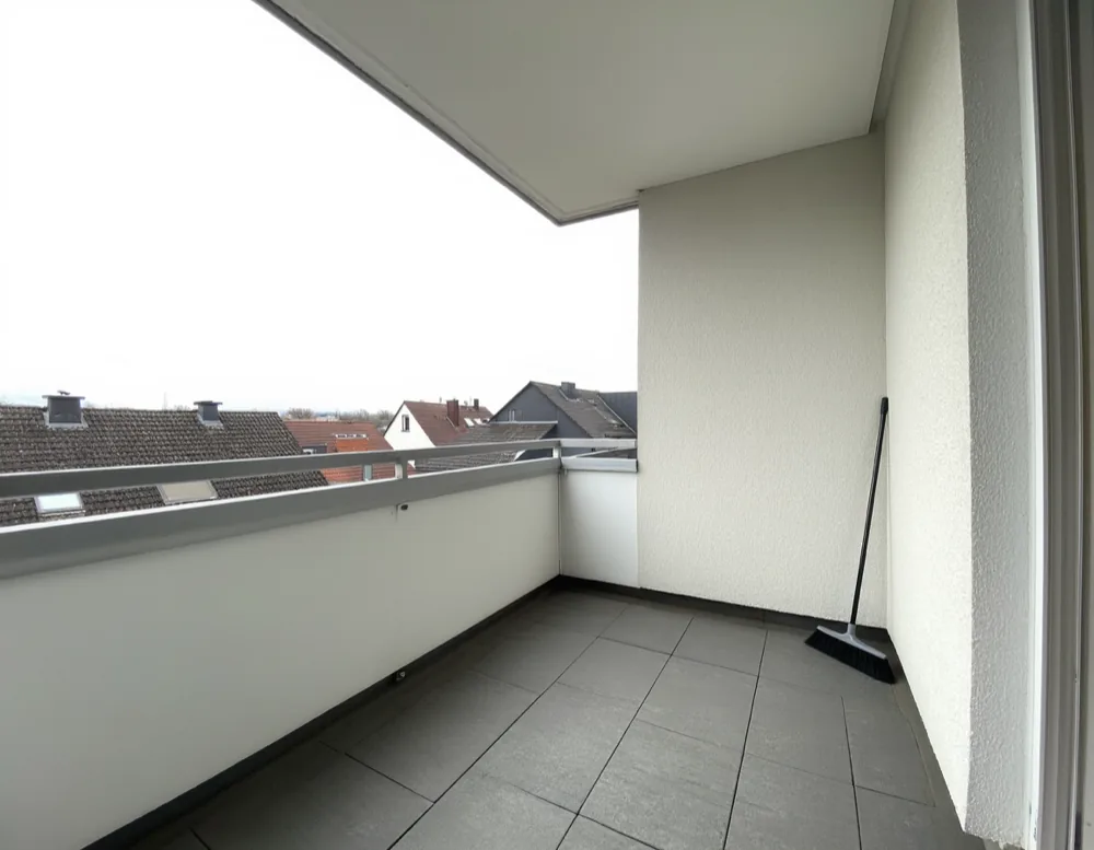 A small swept apartment balcony with a broom against the wall