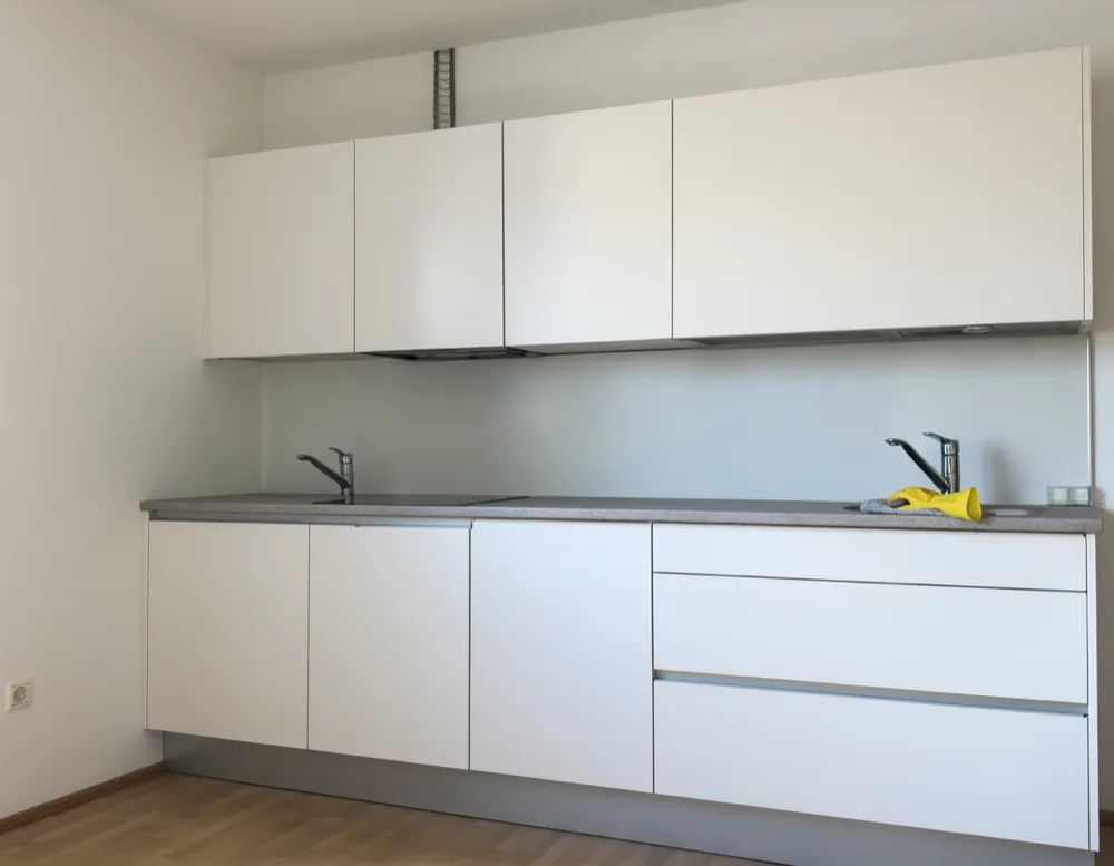 A yellow rubber glove and a folded cloth left on the worktop of a plain white apartment kitchen